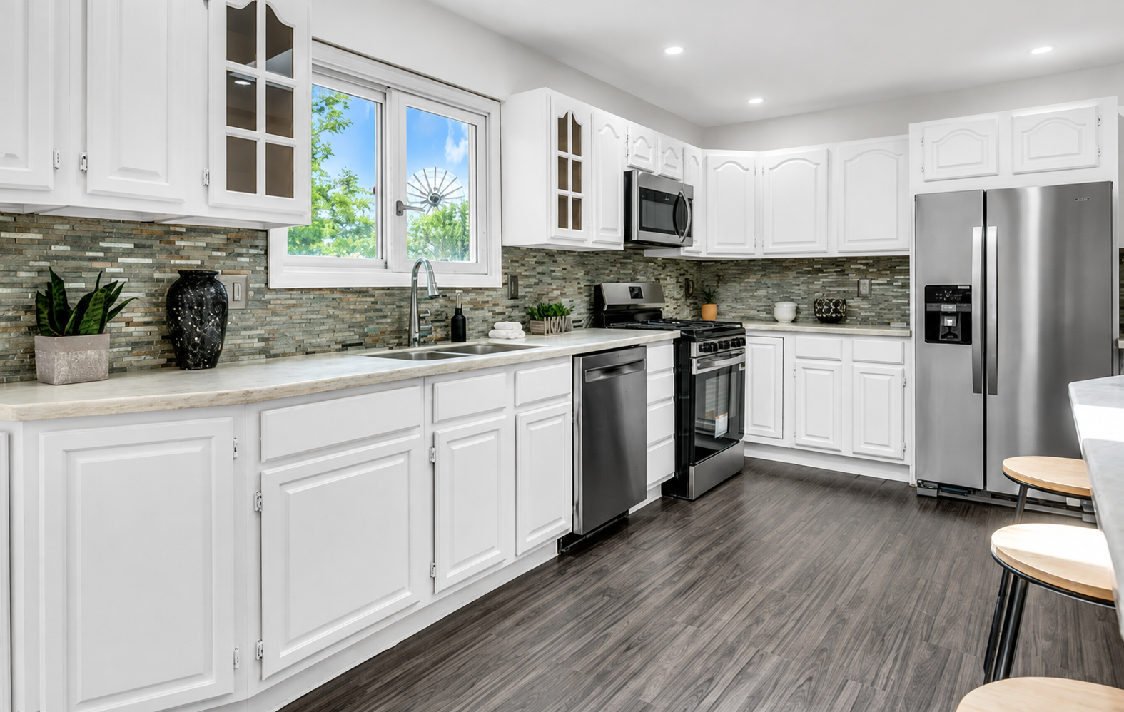 Refreshed white kitchen with mosaic tile backsplash and gray plank flooring
