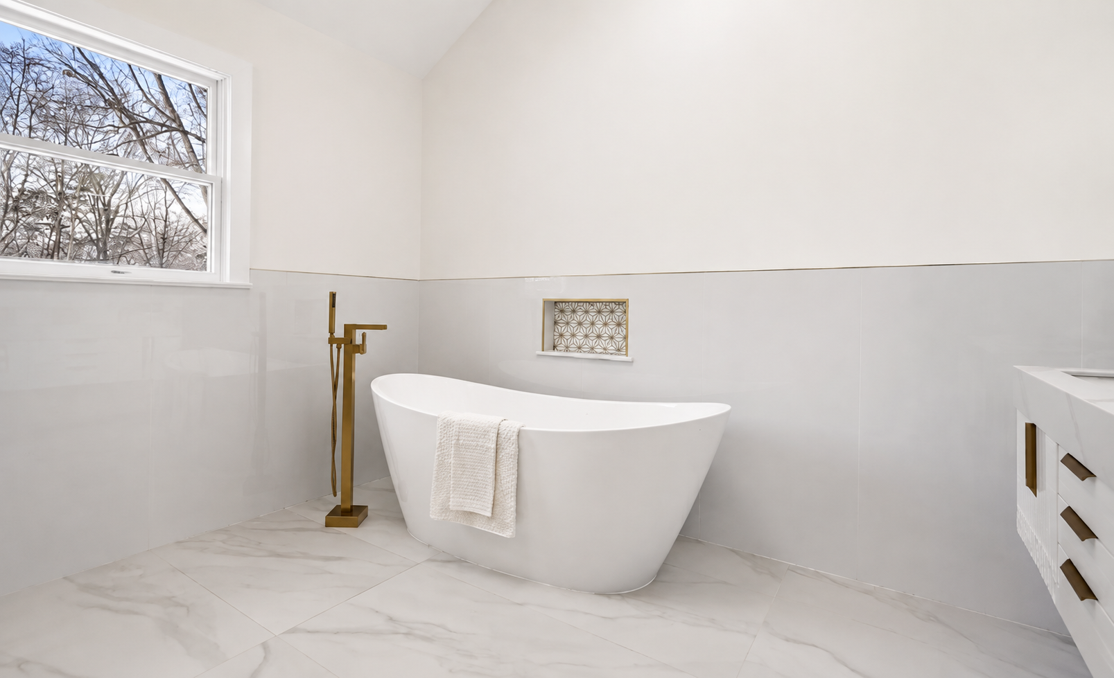 Primary bathroom with freestanding soaking tub and brass floor filler