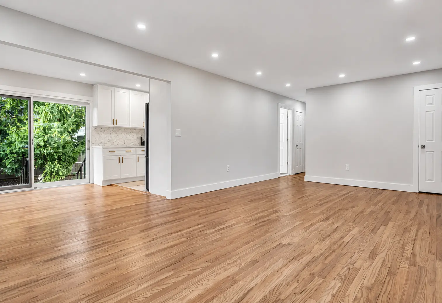 Open living area with red oak floors, recessed lighting, and sliding doors