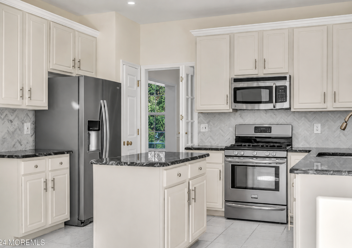 White kitchen with center island, herringbone backsplash, and stone counters