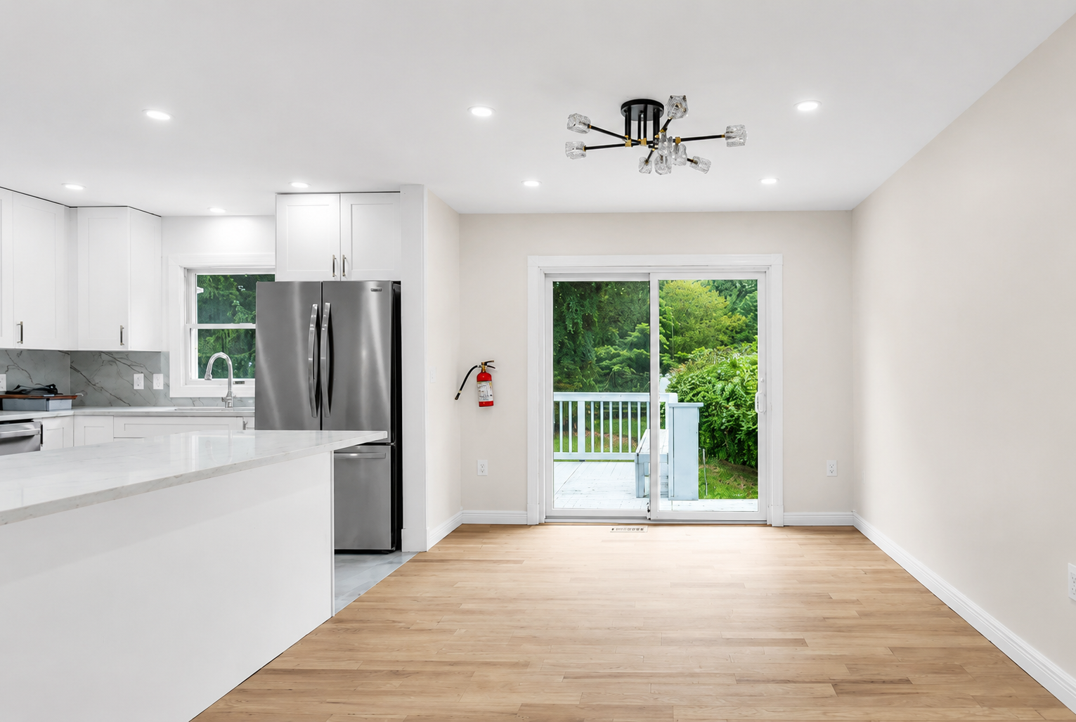 Kitchen and dining area with quartz peninsula and sliding glass door to a deck