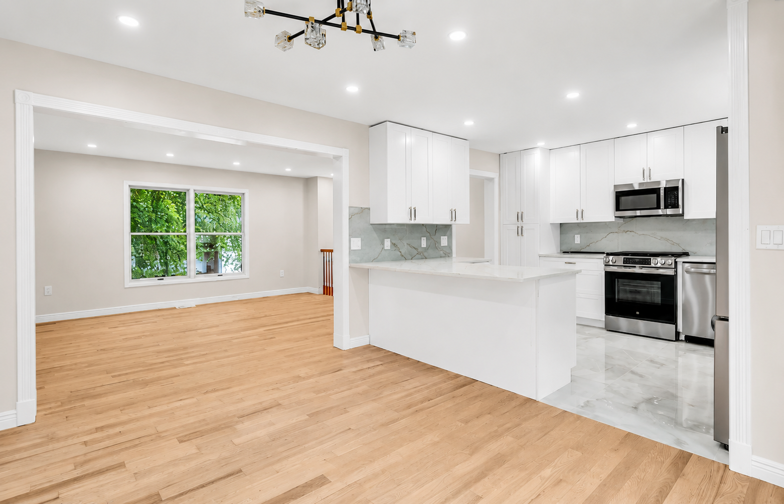 Open concept kitchen with peninsula island opening onto a hardwood living room